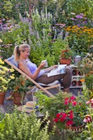 Woman relaxing on patio drinking tea and reading  garden magazine.