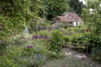 Mixed vegetables and flowers in cottage garden, woven hazel plant supports