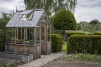 Small wooden greenhouse in cottage garden