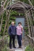 View through rustic arch to couple standing in garden

