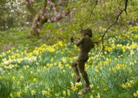 A figurative sculpture surrounded by Narcissus in the Spring Garden at Thenford Gardens and Arboretum, Thenford, Banbury, Oxfordshire, UK