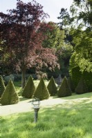 Sundial on a sloping lawn with an avenue of clipped yews below at the Old Rectory, Netherbury, Dorset in May