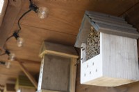 A line of bee hotels, set in the rafters of a summer house, attracts solitary bees. Some of the bee hotels are homemade and others bought. 