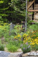 Front garden in Quebec with Bear sculpture set in bed of flowering perennials - August