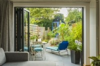 View through bifold doors into long narrow town garden in summer with garden studio. August