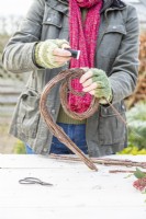 Woman using wire to secure the bundle of sticks