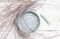 Birch sticks, circular tray and short lengths of wire laid out on a wooden surface