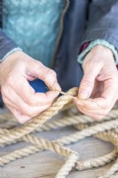 Woman tying string to mark the centre of both lengths of rope