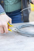 Woman using pliers to cut a length of wire