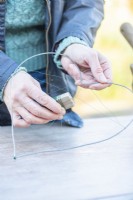 Woman using the thin wire to make a web over the thick wire frame
