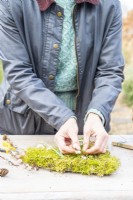 Woman placing a pussy willow sprig in the moss heart