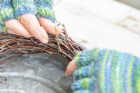 Woman using wire to hold the birch sticks together to create a home made wreath