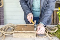 Woman nailing the rope to the base of the tray