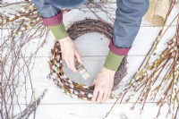 Woman wiring the pussy willow to the homemade birch wreath