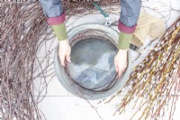 Woman placing birch sticks around the edge of the metal basin to make a homemade wreath