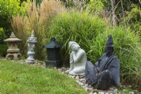 Asian sculptures and Chinese lanterns in rock border in backyard garden in summer, Quebec, Canada - August
