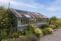 Large potting shed painted green, in the summer flower filled garden