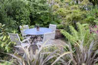 Seating area surrounded by lush foliage in a June garden