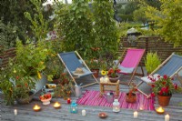 Decked roof terrace with deckchairs, container grown herbs and vegetables and raised bed.