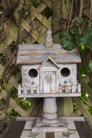 Rustic wooden birdhouse on a stand inside gazebo in backyard country garden, Quebec, Canada - August