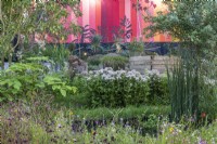 A pink striped panel backdrop contrasts with a drought tolerant garden.