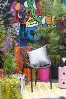 A small town courtyard inspired by Pop Art and Street Art with a colourful mural, and bold planting in assorted metal containers (vintage and repurposed kitchen bins).