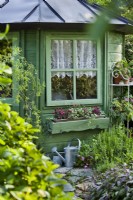 Summerhouse with floral window box and watering can.