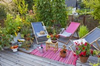 Decked roof terrace with deckchairs, container grown herbs and vegetables.