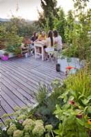 Women sat enjoying cake and drinks on roof terrace.