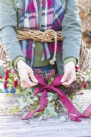 Woman tying a bow at the base of the wreath