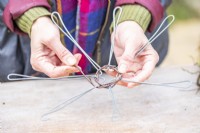Woman weaving birch twigs through the wire frame
