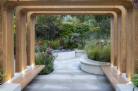 Uplit timber arches create a dramatic entrance to a sunken sanctuary garden. Rills and pools bring the sound of water. Raised beds are filled with bold autumn colours from red hot pokers, coneflowers, rudbeckias and dahlias.