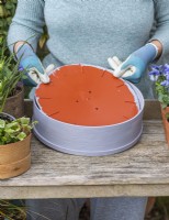 Step-by-Step Planting Wooden Flour Sieves with Spring Flowers. Step 2: create a sturdy base over the mesh with a cut-down, plastic plant saucer.