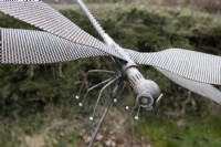 A dragonfly made from recycled metals including a washing machine drum, drill bit and washers.