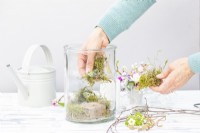 Woman placing moss in the large glass container