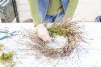 Woman wiring moss to the wreath