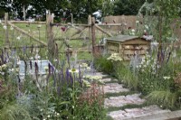 'The Earth Smiles with Flowers' at BBC Gardener's World Live 2021 - cottage garden with rustic brick and camomile path, beehive and muted perennial planting