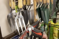 A variety of garden tools for sale in a garden centre including forks and trowels. 