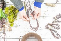 Woman tying birch twigs together at each end
