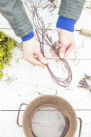 Woman tying birch twigs together at each end
