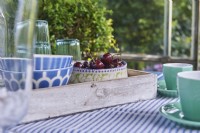 A summer table set in a summer house with cherries and glasses and coffee cups.