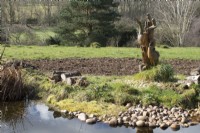 Wooden carved bird statue next to the wildlife pond in John's Garden at Ashwood Nurseries - Kingswinford - Spring
