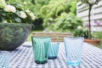 blue glasses on the tablecloth with view into the garden