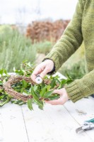 Woman using wire to secure the laurel to the wreath
