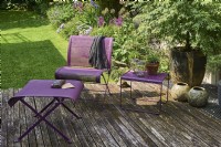 Purple furniture on wooden deck with view to garden behind
