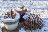 Planters with cutback plants left outdoors in backyard garden with snow on the ground in late autumn, Quebec, Canada - November