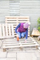 Woman using jigsaw to cut along the line marked on the pallet