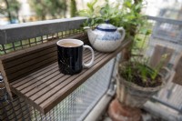 Upcycled shelf on a balcony. Made from the balconies old wooden decking planks after it they were replaced. 
Cup of tea with milk. 
