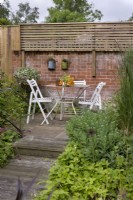 Seating area in back garden of country cottage with Sedum 'Autumn Joy', Calamagrostis acutifolia 'Overdam'
