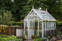 Victorian style greenhouse with chain water collector in a galvanised container.  RHS No Dig Allotment Demonstration Garden in Association with Charles Dowding and Stephanie Hafferty